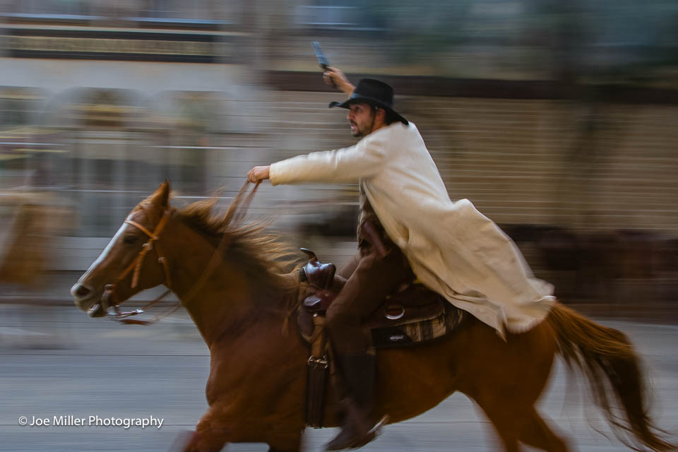 man riding horse with gun in his hand